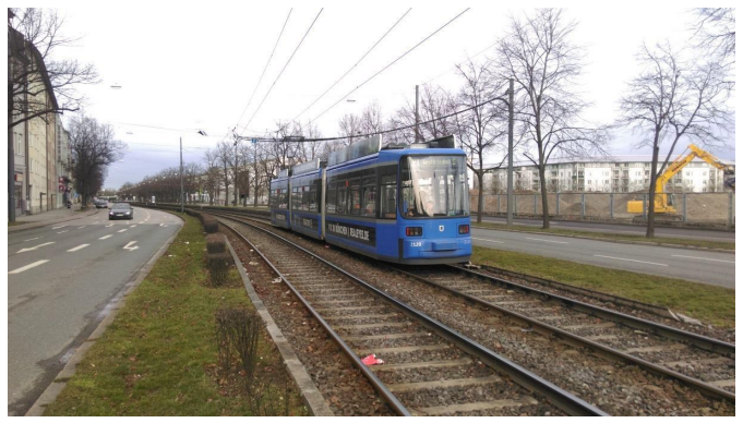 Et bl&aring;t letbanetog k&oslash;rer p&aring; et spor langs en vej i et byomr&aring;de. Letbanen er adskilt fra vejbanen, men k&oslash;rer parallelt med biltrafikken og reguleres af vejsignaler